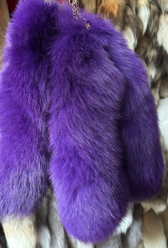 Purple fur tail hanging against a background of various furs.