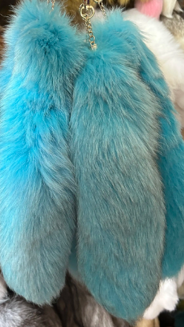Multiple blue fluffy tail keychains on a blurred background